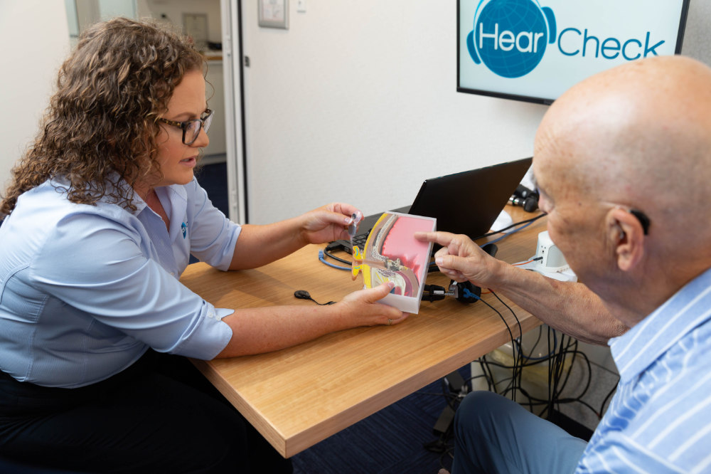 audiologist explaining hearing loss with ear model audiologist explaining hearing loss with ear model