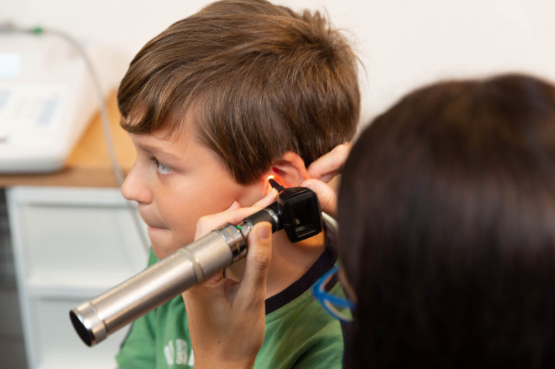 boy with audiologist inspecting ear boy with audiologist inspecting ear