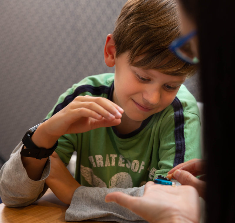 boy with audiologist looking at hearing aid boy with audiologist looking at hearing aid