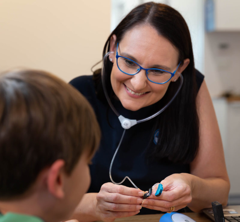 boy with audiologist showing hearing aids